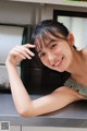 A young woman leaning on a counter in a kitchen.