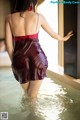 A woman in a red dress standing in a pool of water.