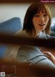 A woman sitting on top of a bed next to a window.