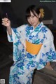 A woman in a blue and white kimono sitting on a bench.