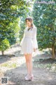 A woman in a white dress standing in the woods.