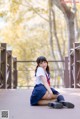 A woman in a school uniform sitting on a bridge.