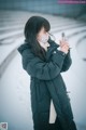 A woman wearing a face mask while standing in the snow.