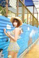 A woman in a yellow and blue bikini and a straw hat.