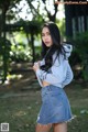 A woman in a denim skirt and a hoodie posing for a picture.