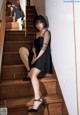 A woman in a black dress is sitting on the stairs.