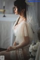 A woman in a wedding dress sitting on a bed.